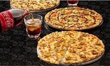 Three large pizzas on a table with a drink being poured